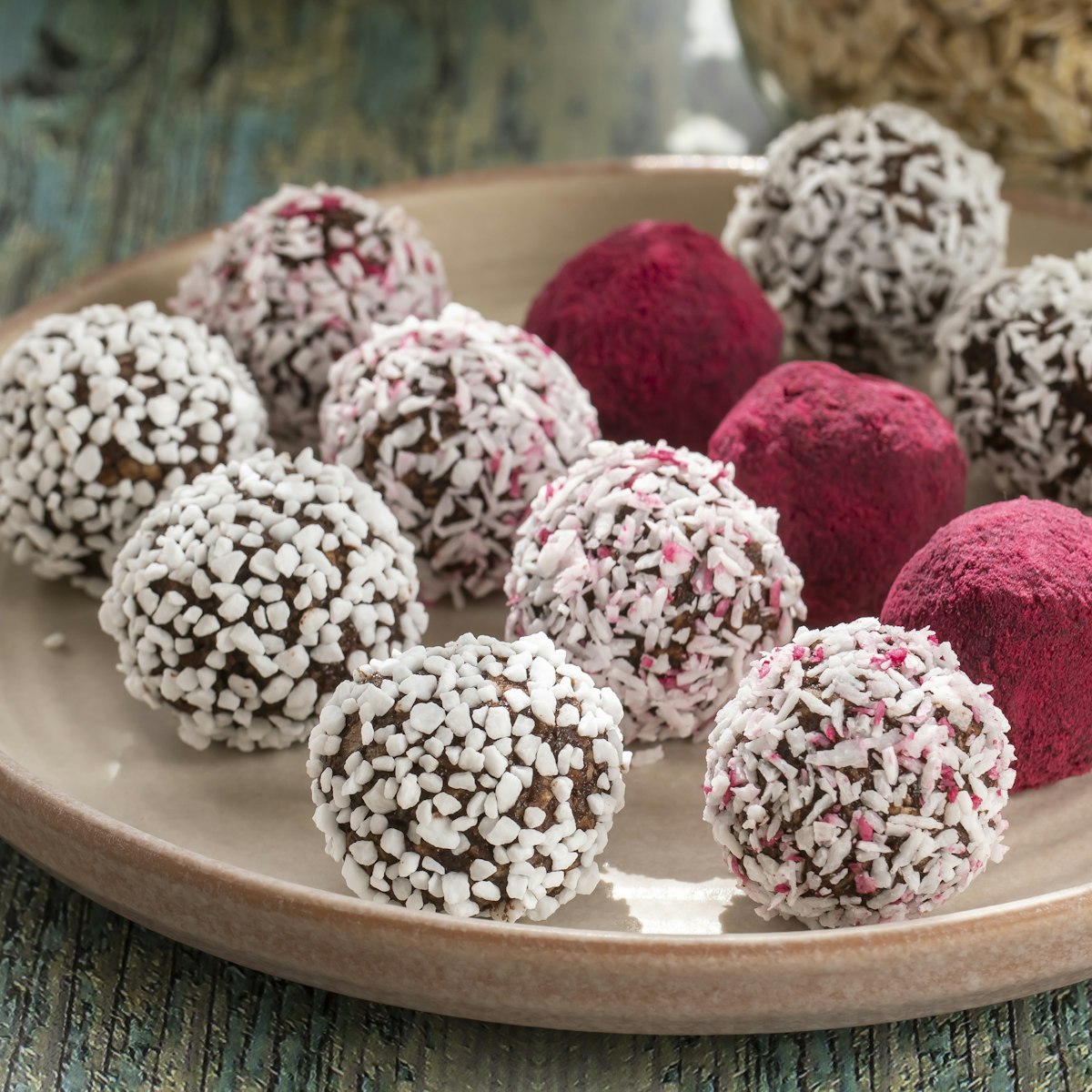 A plate of chocolate balls coated in coconut and pink sprinkles.