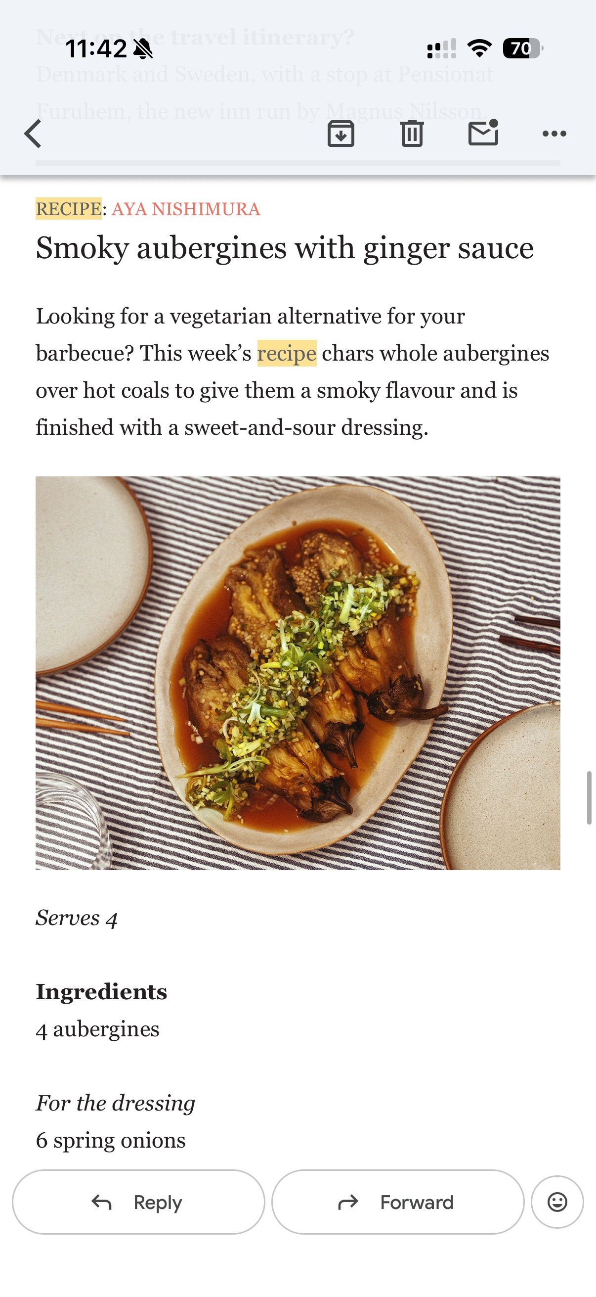 Charred aubergines arranged on a serving plate with ginger dressing and chopped green onions.
