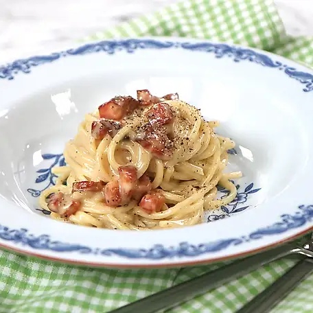 Spaghetti carbonara with pancetta on a blue-and-white plate